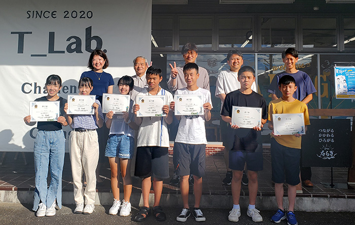 The children, holding their certificates of completion, lined up in the front row, while the adults lined up in the back row for a photo shoot.